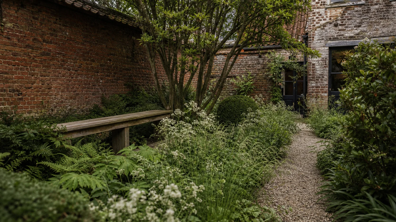 Mature brick courtyard planted with ferns and flowering perennials